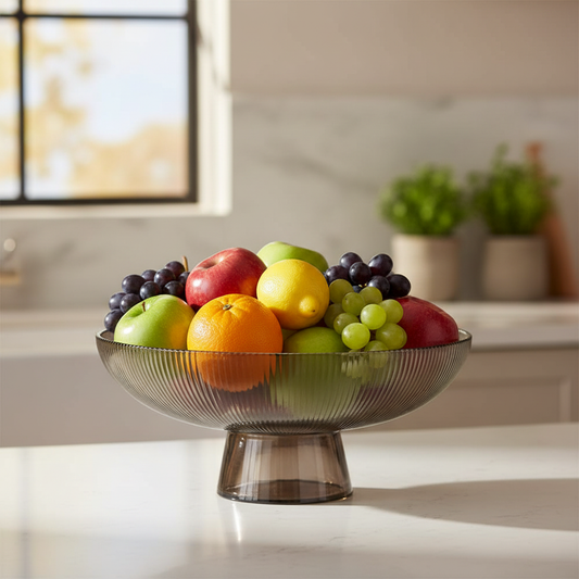 Ribbed smoked glass pedestal fruit bowl filled with fresh colourful fruit on kitchen counter